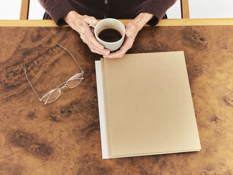 Hände mit Tasse, leere Ordner und Lesebrille auf einem Tisch, Illustration